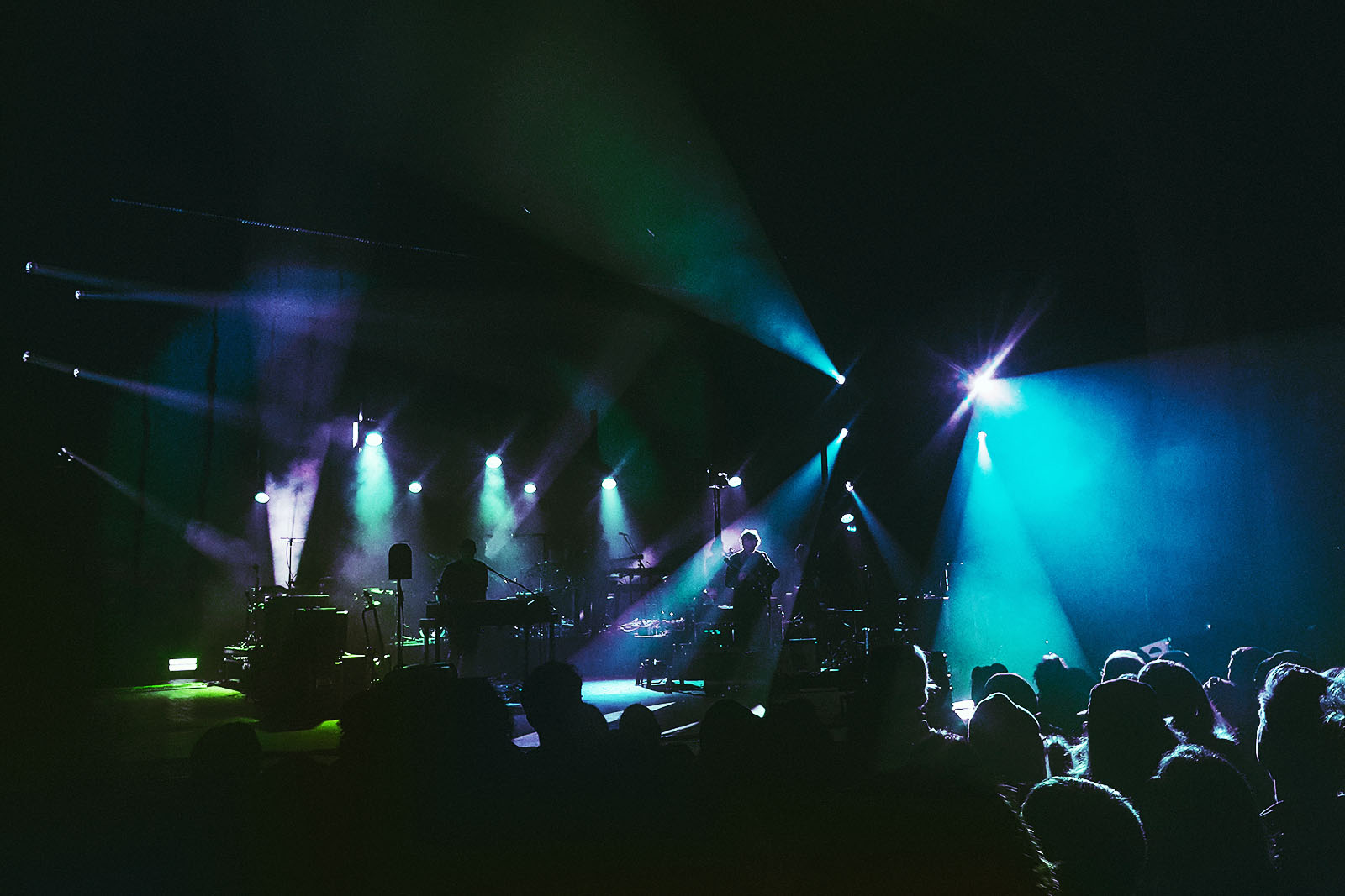 The Bees Knees performing live on stage with spotlights shining in the dark.